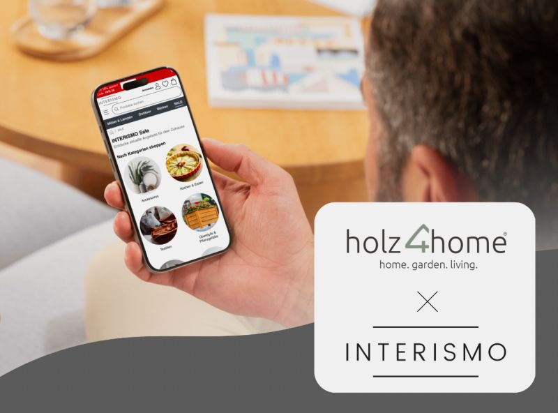 Mann hält ein Smartphone mit dem INTERISMO-Onlineshop neben dem holz4home-Logo in der Hand