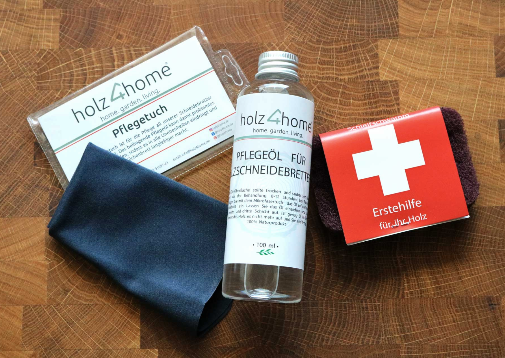 Pflegeset von holz4home mit Pflegetuch, Pflegeöl und Schleifschwamm auf einer Eichenfläche